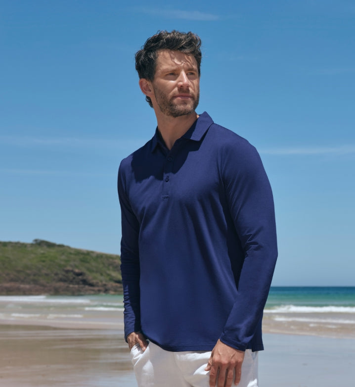 Man wearing a Solbari blue long-sleeve polo shirt on a beach.