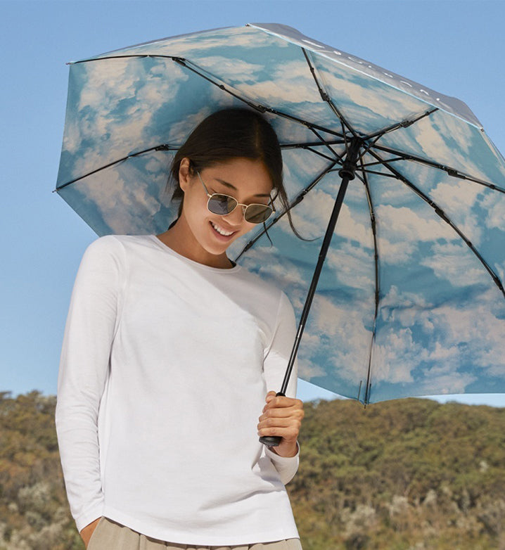 Woman holding an UPF 50+ umbrella, wearing UPF 50+ Solbari protective clothing.