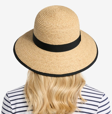 Beige straw hat with black band worn by a person in a striped shirt on a white background
