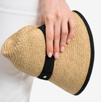 Hand holding a straw hat with a black band on a white background
